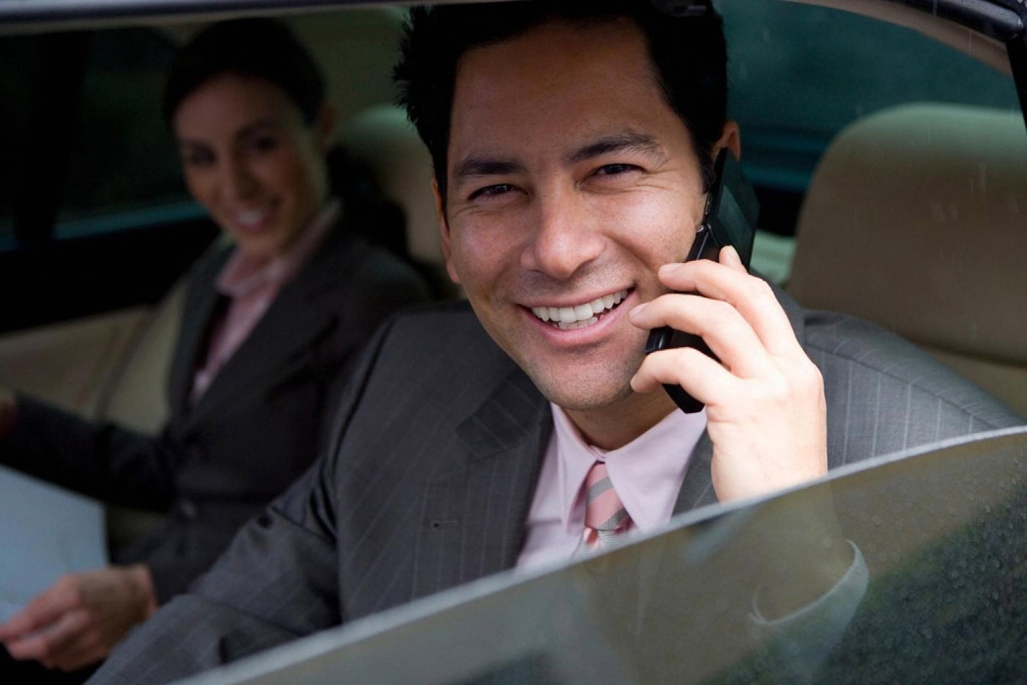 Businessman in a suit taking a phone call from the back seat of a chauffeur-driven car in Dubai