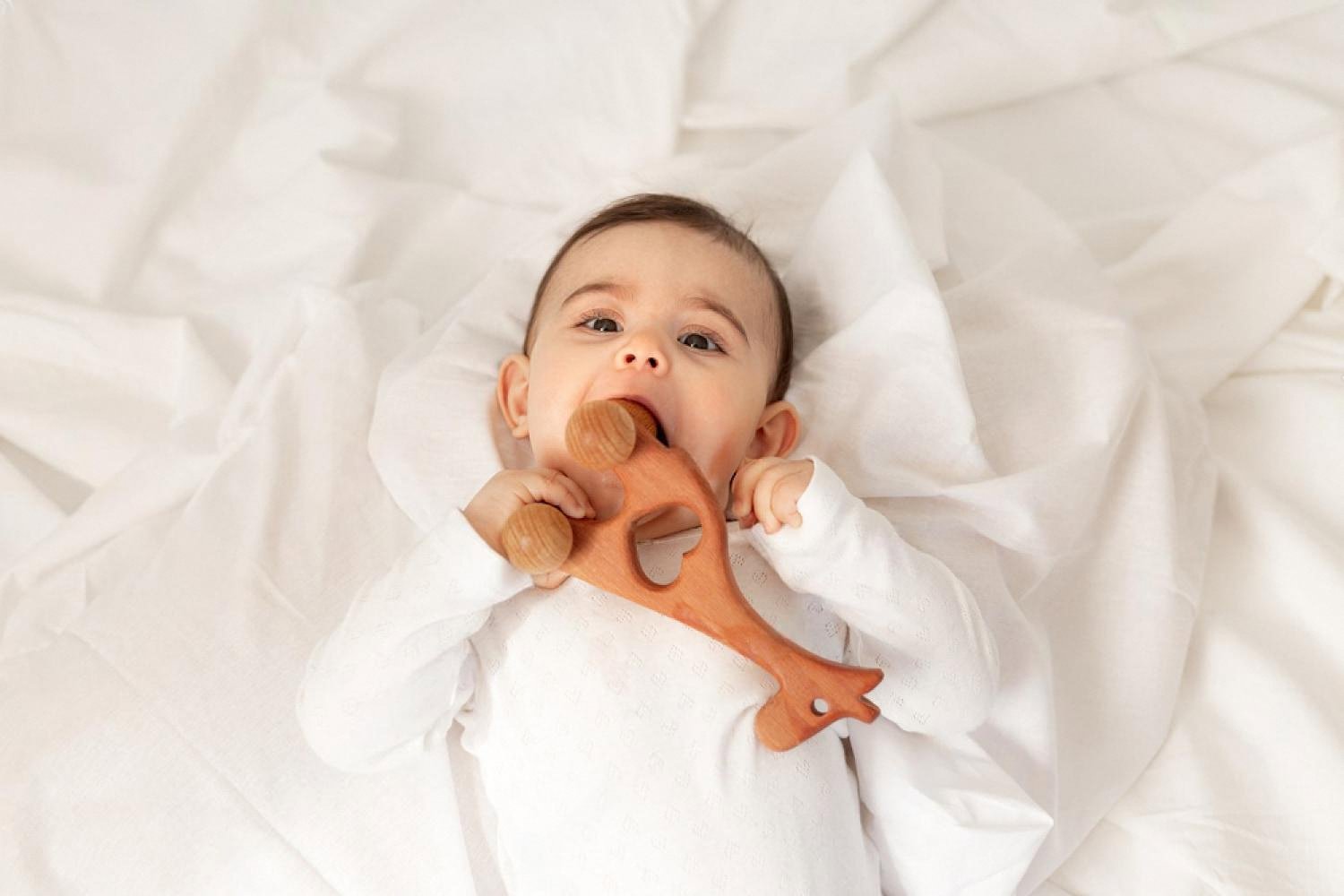 Baby chewing on a wooden teether made from natural, untreated wood